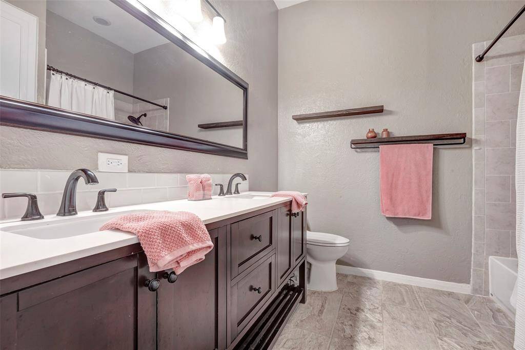 Secondary bath with tiled tub/shower combo and double vanities.