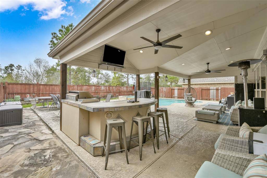 A view of the bar and extended patio with recessed lights and ceiling fans.