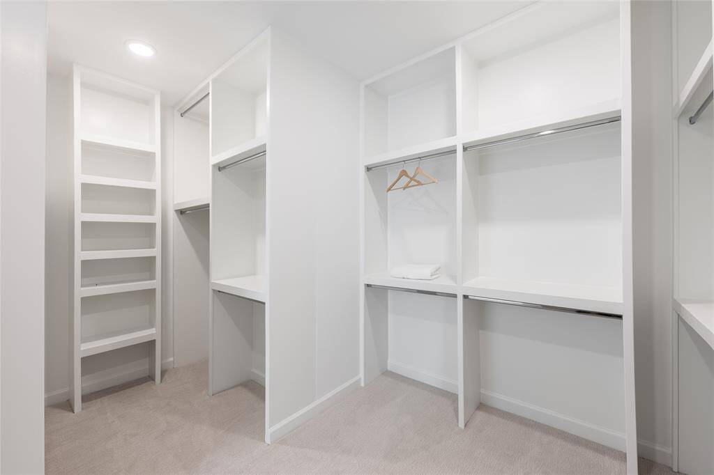 Step into a spacious, thoughtfully designed primary closet, where custom built-ins provide the ultimate in organization and style. With abundant shelving and hanging space everything has its place—making it easy to keep your wardrobe and accessories neatly arranged.