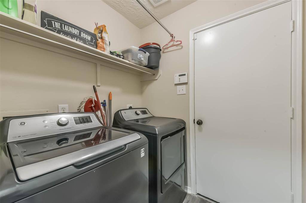 No more laundry day dread! This dedicated laundry room offers full-size appliances, overhead shelving, and a direct path to the garage—making multitasking just a little bit easier.