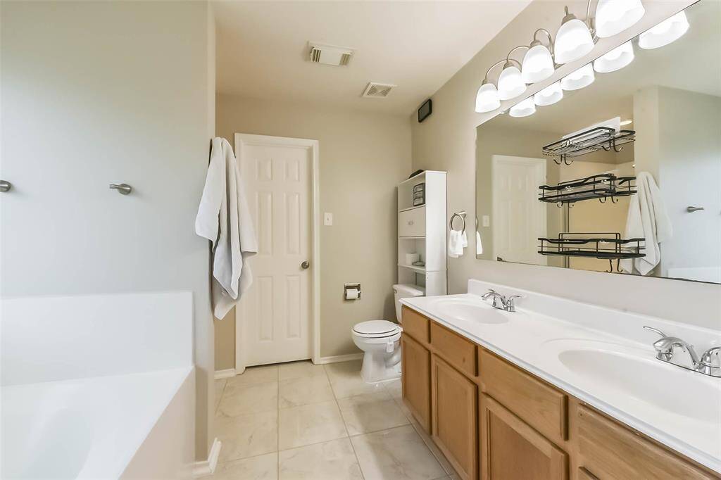 Double sinks and zero clutter fights. This en-suite bathroom offers ample counter space, updated lighting, and neutral finishes that complement any style.