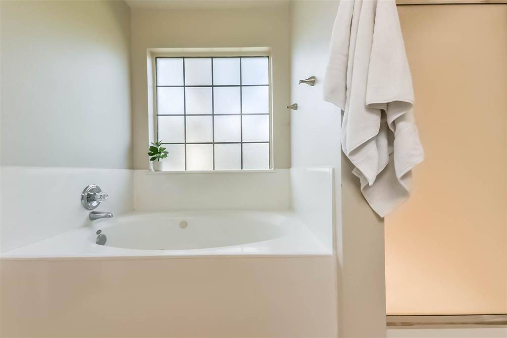 Bubble baths and spa days start here. A deep soaking tub sits beneath a frosted window for privacy and light, while a separate walk-in shower completes the perfect setup.