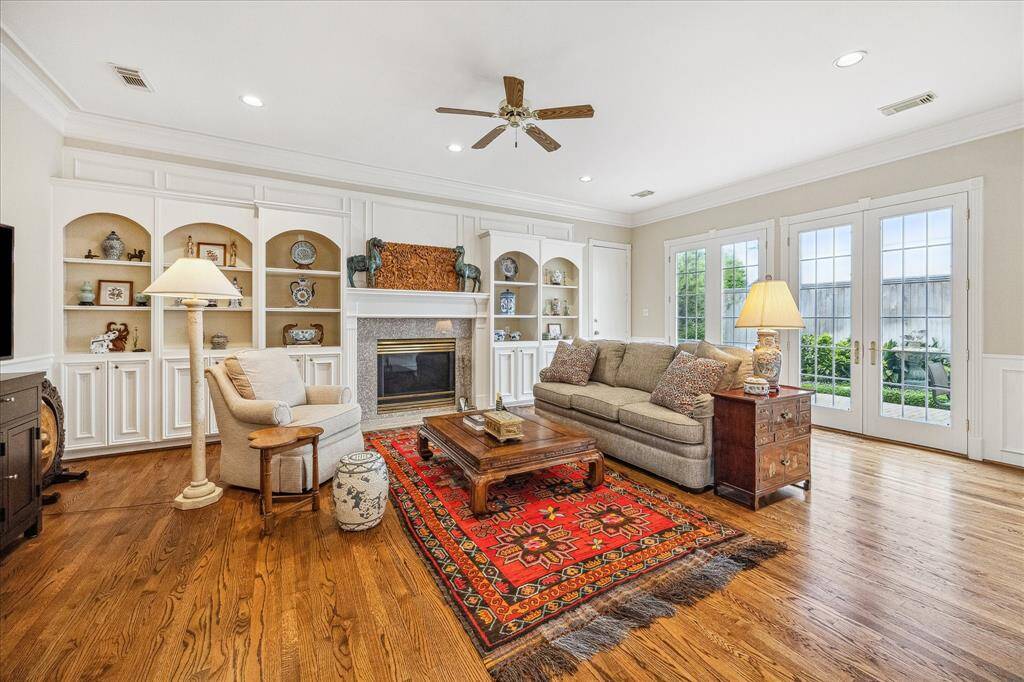 The family room is a lovely gathering space for the family with its fireplace, built-ins beautiful hardwood floors and wall of french doors viewing the backyard.