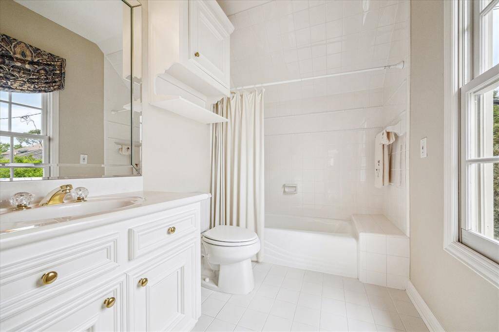 This is an ensuite bath with tub/shower and spacious sink vanity. The white decor & large windows allows a light/bright feel.