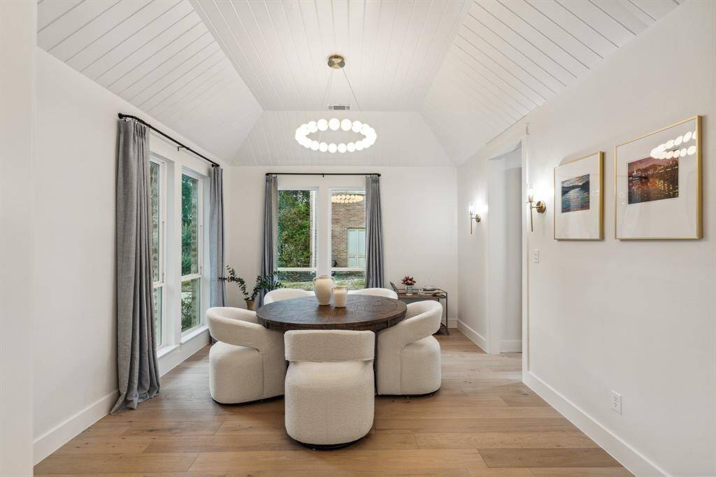 The formal dining features a beautiful wood detailed ceiling, sconce lighting, chandelier, and picture windows and this room is connected to the kitchen via the hallway on the right side of the picture.