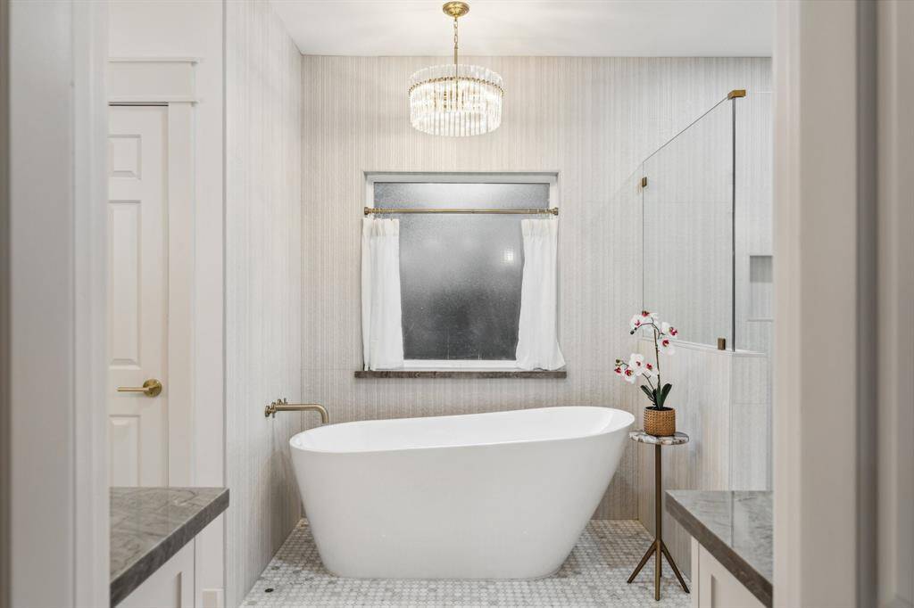 Primary bathroom with soaking tub, new hardware, floor to ceiling wall tile, frameless glass shower, custom vanities, and all new fixtures and lighting.