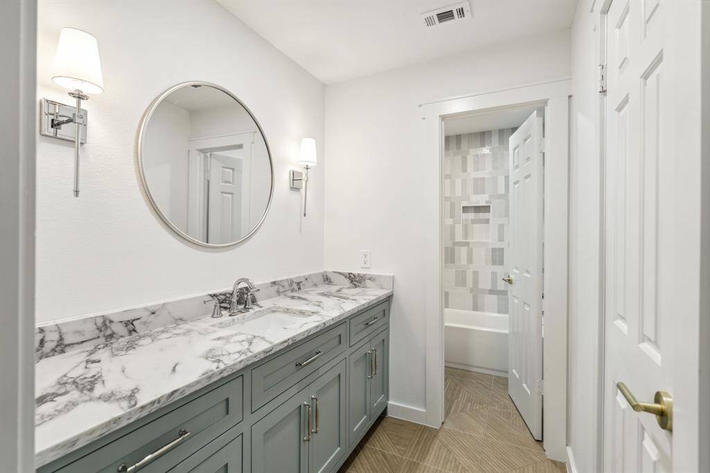 En-suite bathroom with quartz counters, new hardware, sconce lighting, all new tile and a walk-in closet.