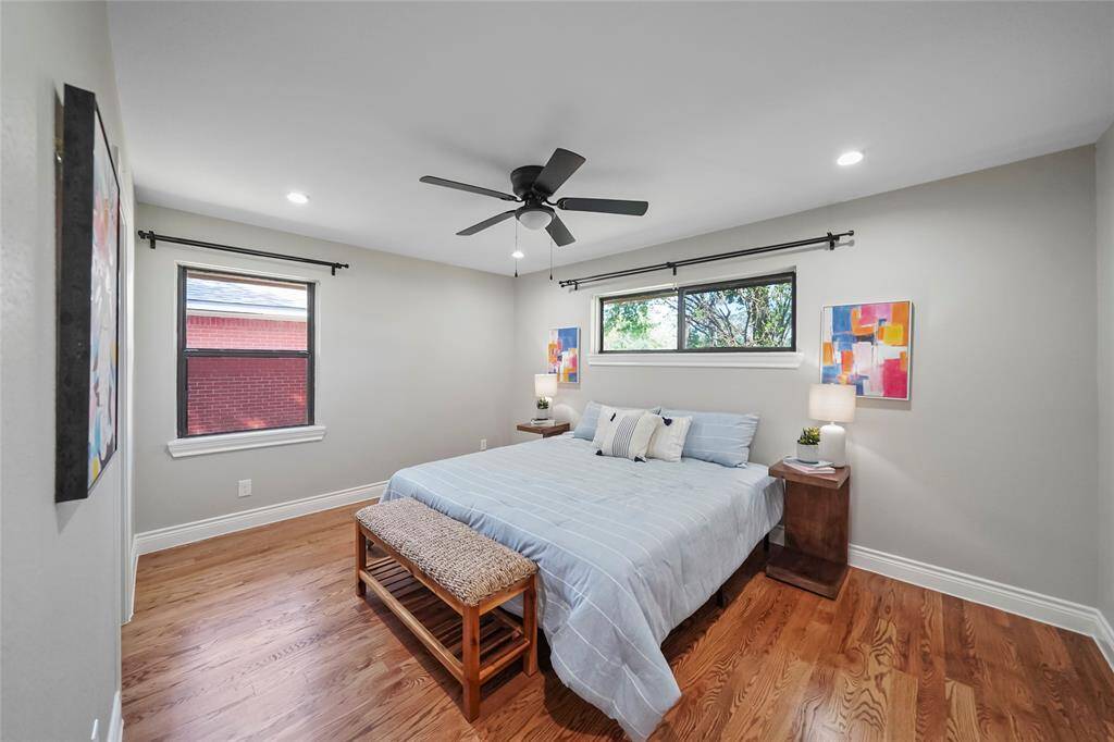 This cozy primary bedroom is spacious enough for a king-sized bed and features recessed lighting, solid wood floors, and an energy-efficient ceiling fan for comfort and style.