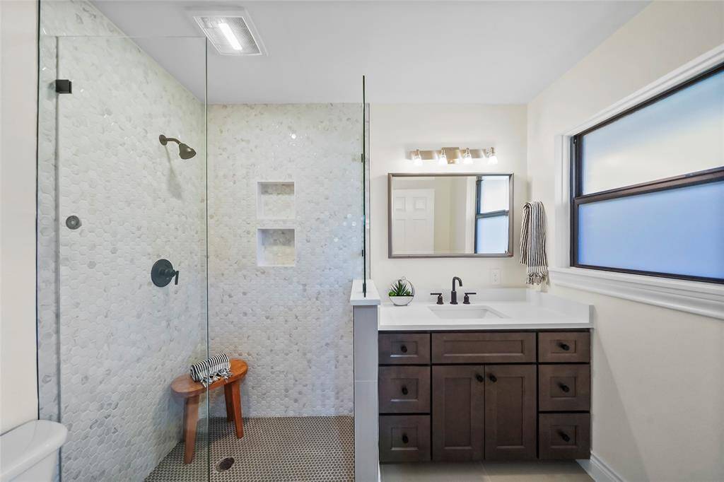 The ensuite primary bathroom features a seamless glass shower, a spacious vanity for all your essentials, and stunning floor-to-ceiling tilework that evokes a high-end spa experience.