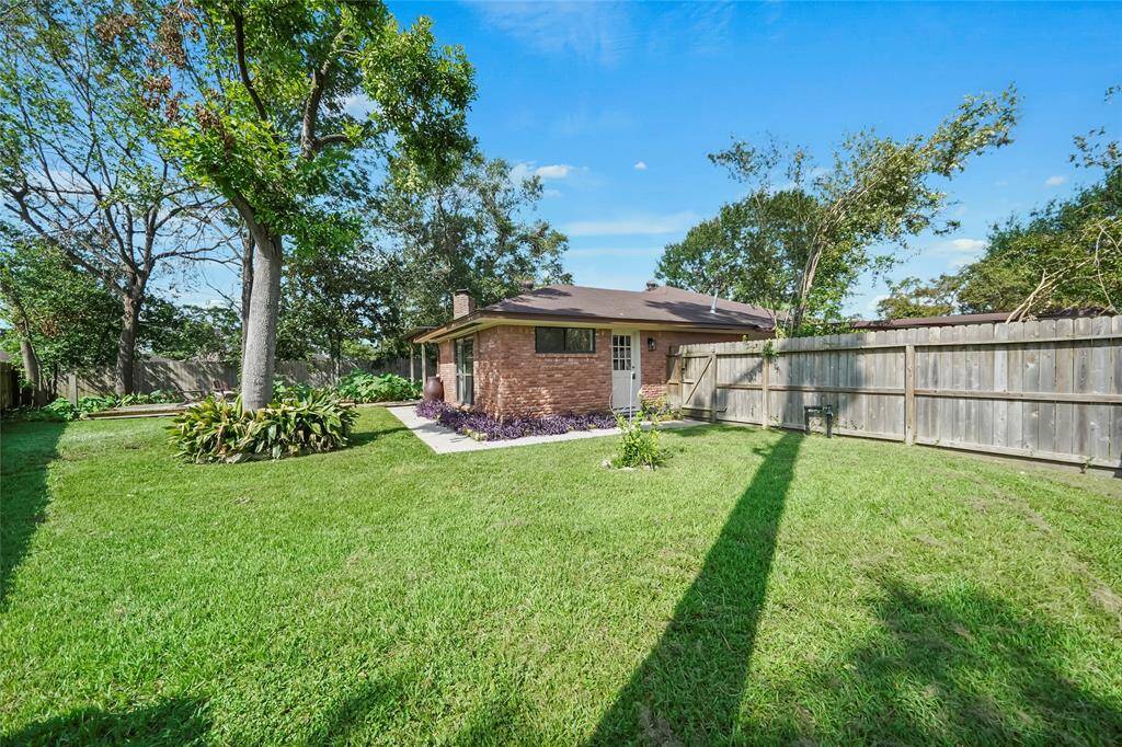 Enjoy a large backyard with endless possibilities, featuring a wood fence for privacy, mature trees, lush landscaping, and multiple seating areas perfect for relaxation or entertaining.