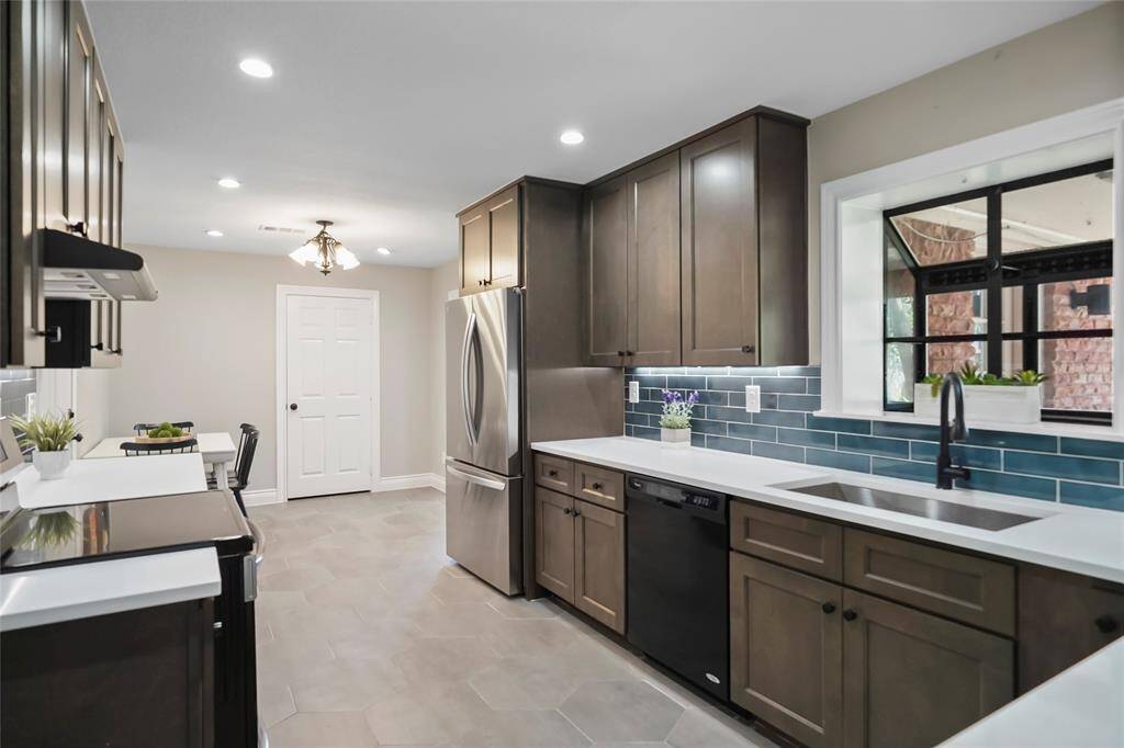 This kitchen is equipped with quartz countertops, tile flooring, recessed lighting, and undercabinet lighting. All the appliances pictured here convey-truly move-in ready. The doorway straight ahead is your walk-in pantry.