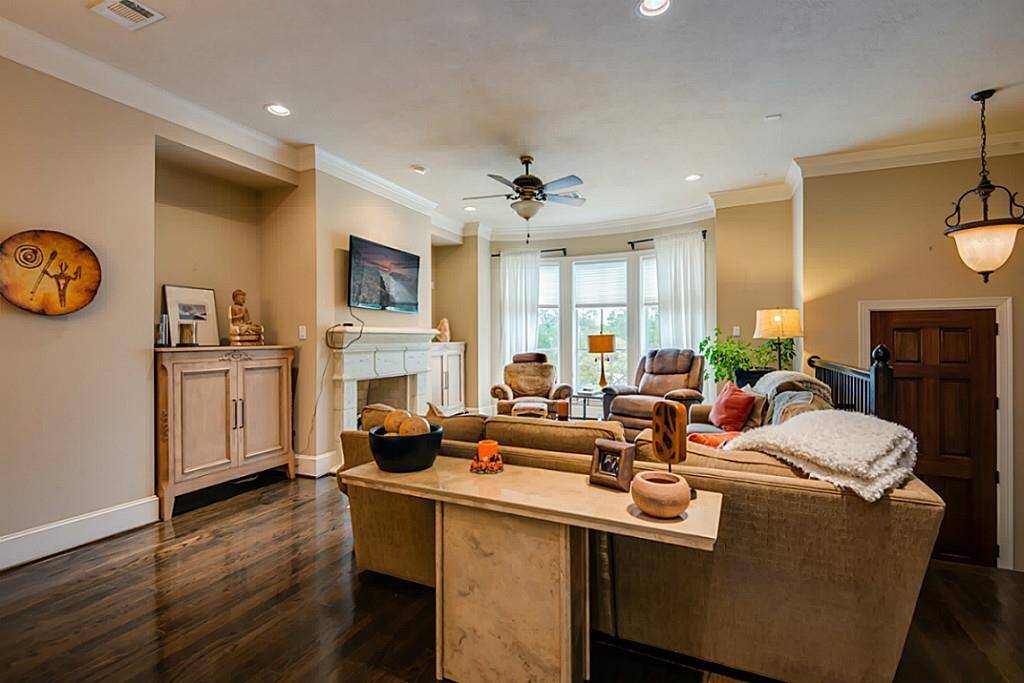 The spacious living room offers gleaming hardwood floors, tall windows, crown molding, and a custom fireplace!