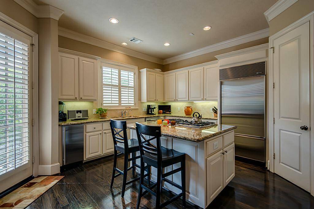 In addition to extra seating, the large island is equipped with a gas burner stove. Notice the generously sized stainless steel refrigerator in close range, as well!