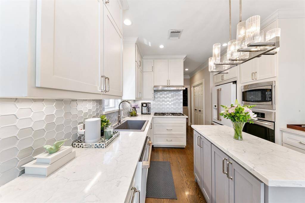 The stunning quartz countertops, under cabinet lighting and tile backsplash add to the ambiance of the kitchen.