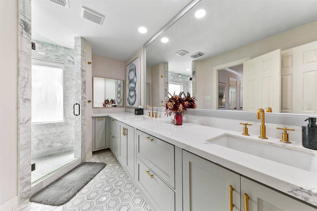 The primary bathroom is both elegant and functional with dual sinks, large walk-in shower, and ample counter space.