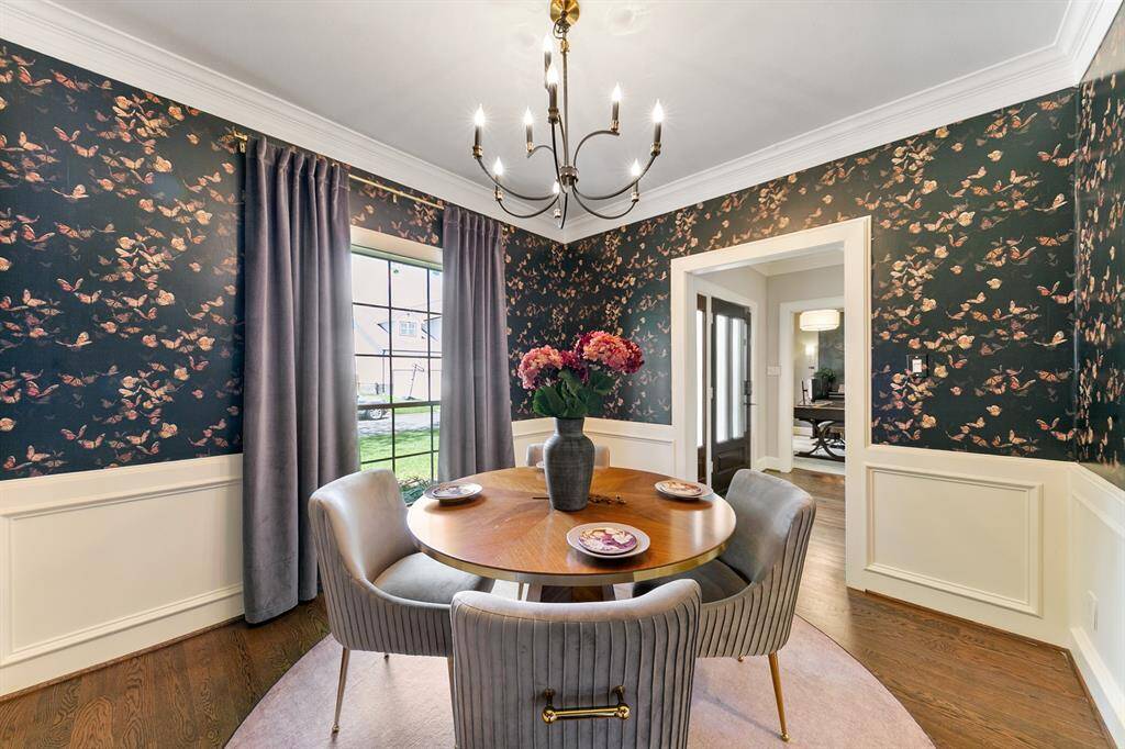 Across the hall from the home office is the stunning dining room.  Be surrounded by luxury with the gorgeous hardwood floors, beautiful wallpaper, crown molding, and updated light fixture.
