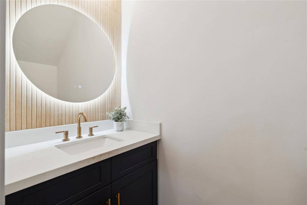 The powder bathroom gives a luxury boutique feel with wood slat panels and a backlit mirror with two color tones as well as a defrost feature.
