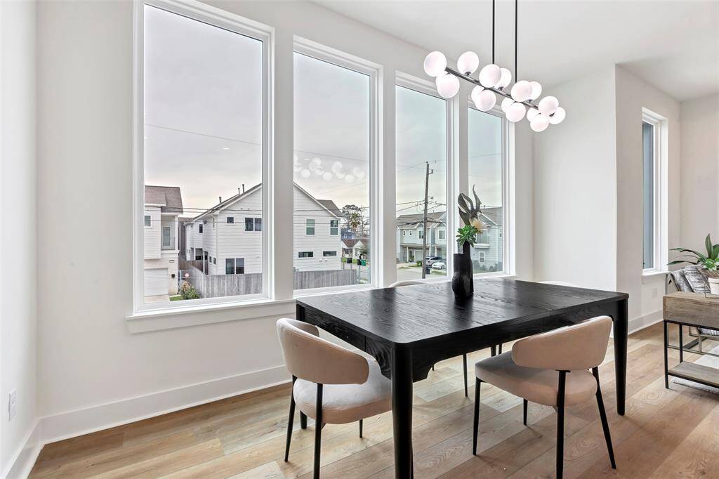 It is bathed in natural light from the adjacent glass window, offering a stunning view of the neighborhood – perfect for enjoying meals with a scenic backdrop.