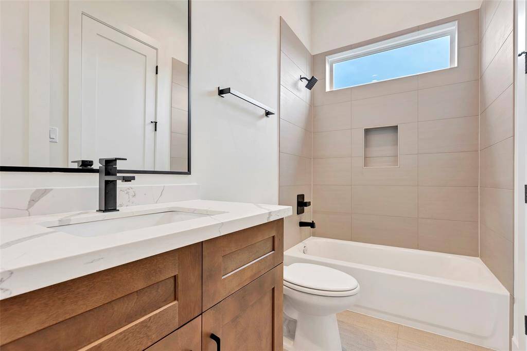 En-suite bathroom featuring a convenient tub and shower combo, along with a sleek single sink and vanity for added comfort and functionality.