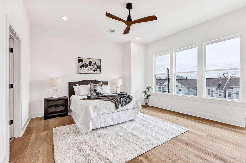 Spacious main bedroom on the third floor, featuring enormous glass windows that provide breathtaking views of the neighborhood, flooding the room with natural light.