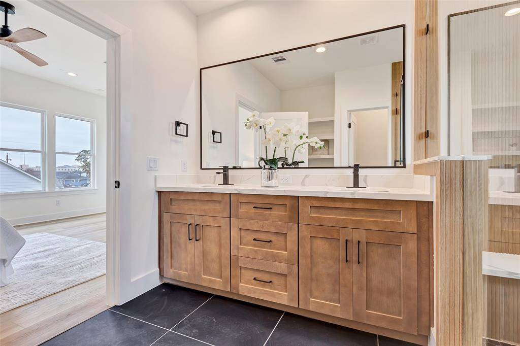 Detailed view of the stylish vanity in the bathroom, with a glimpse of the spacious main bedroom just through the bathroom door.