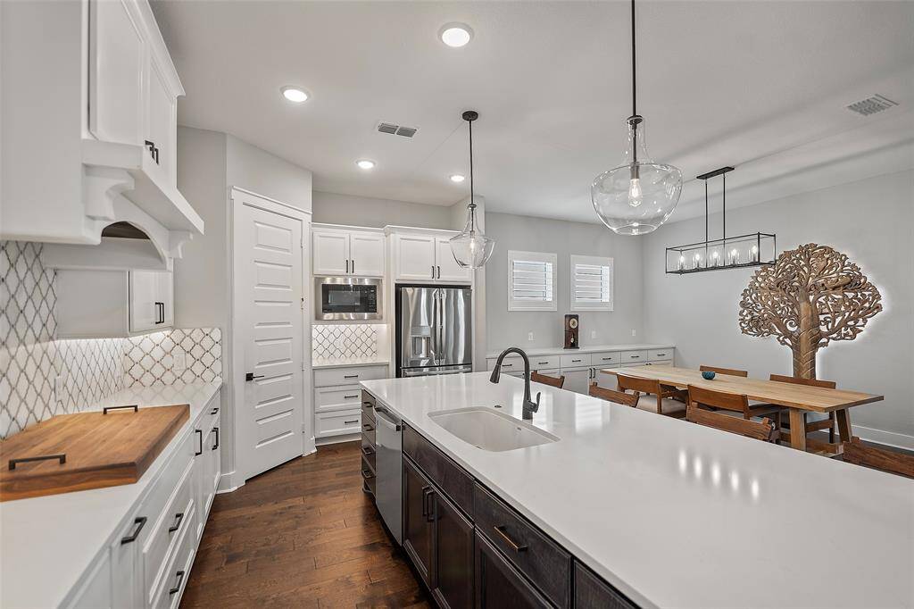 The crisp white cabinets adorned with Quartz countertops, and beautiful custom tile backsplash just creates such an inviting kitchen that every chef will love!