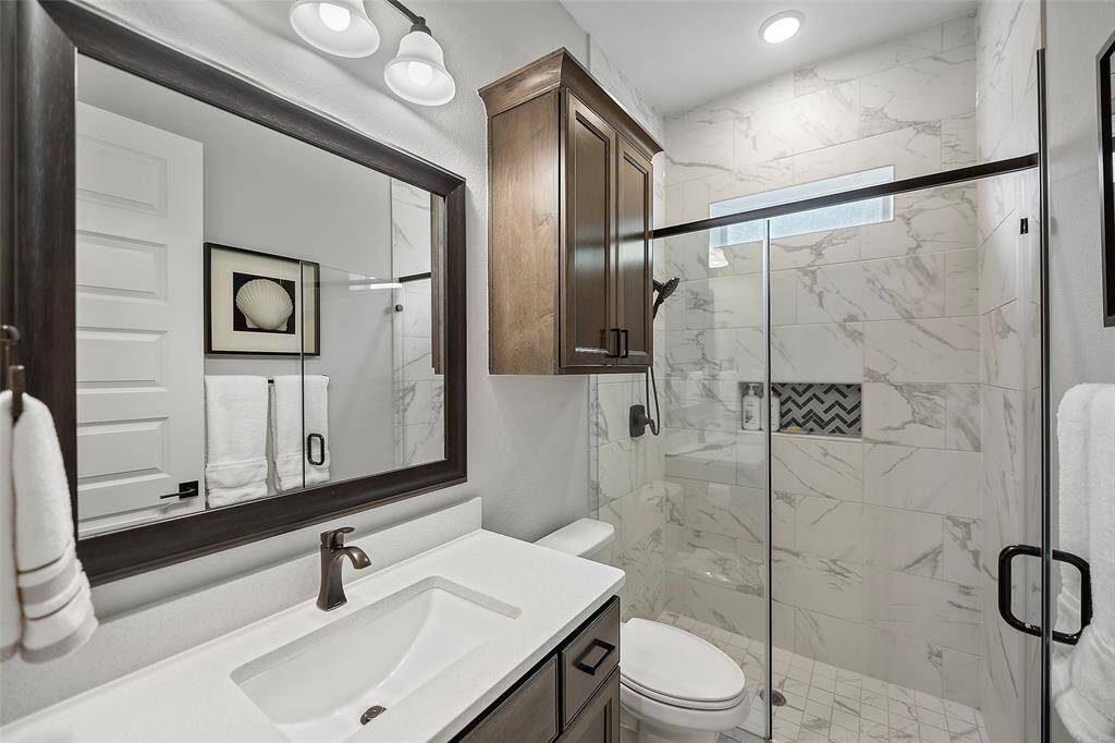 This full-sized bathroom is straight out of a magazine! Gorgeous dark stained cabinets, classic fixtures and an oversized glass enclosed shower with fantastic tile surround, & pocket window!