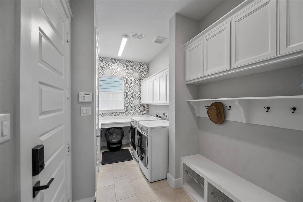 WOW! Who says the combined MUD room/utility room has to be boring? This room is anything but, with so many cabinets for storage, hooks to hang backpacks, coats and hats and even space to fold clothes! This room has it all including a custom featured tile wall and an extra built-in sink too!