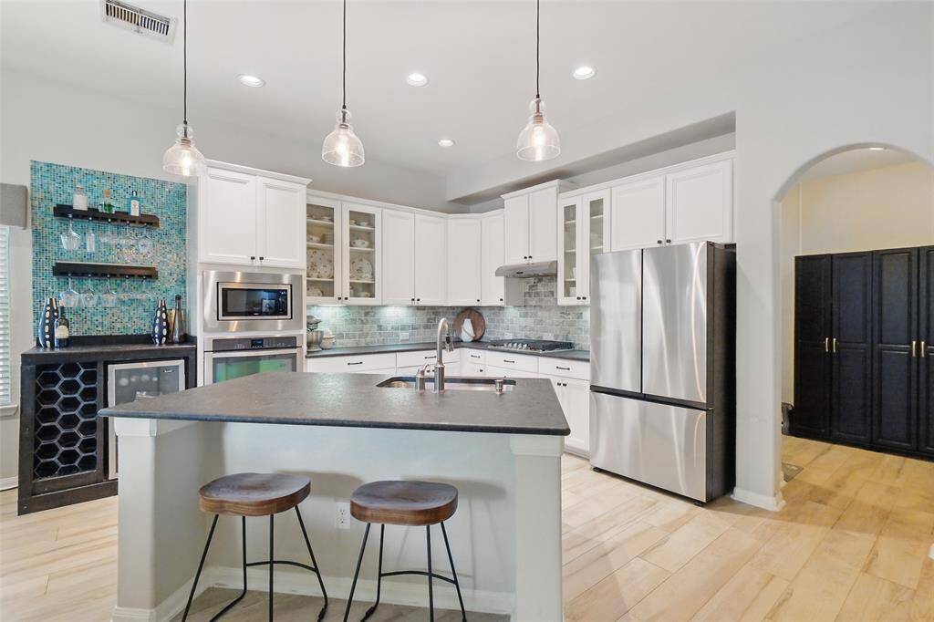 Island kitchen with custom wine bar with wine fridge.