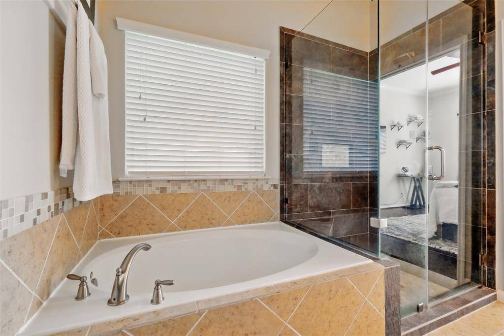 Soaking tub and large shower with frameless glass doors.