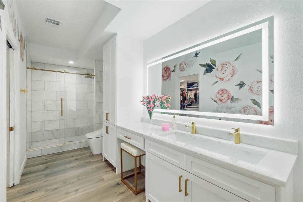 Custom vanity with marble top, deep sink, and brass hardware. The vanity mirror is a touch light display.