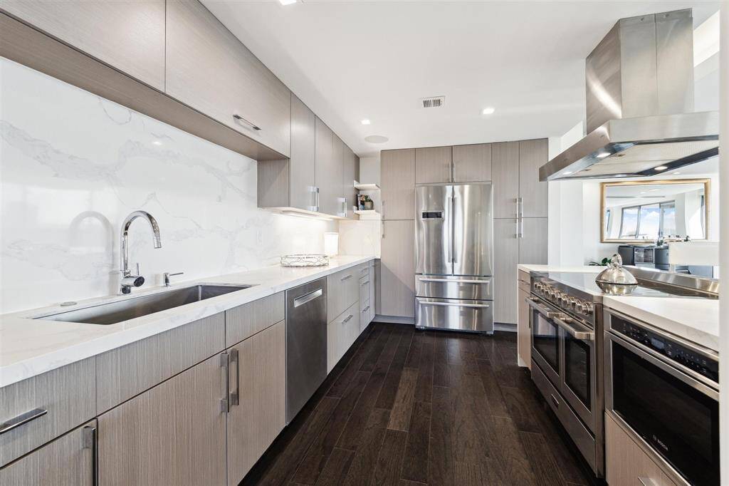 Equipped with top-tier Bosch appliances, including a refrigerator, dishwasher, and under-counter microwave, this kitchen also features a Verona commercial-grade double oven with a warming drawer and an electric range.