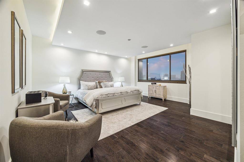 Hotel-like primary suite featuring engineered hardwood, tray ceiling with integrated LED lighting, recessed lighting, hardwired surround sound, and stunning views.