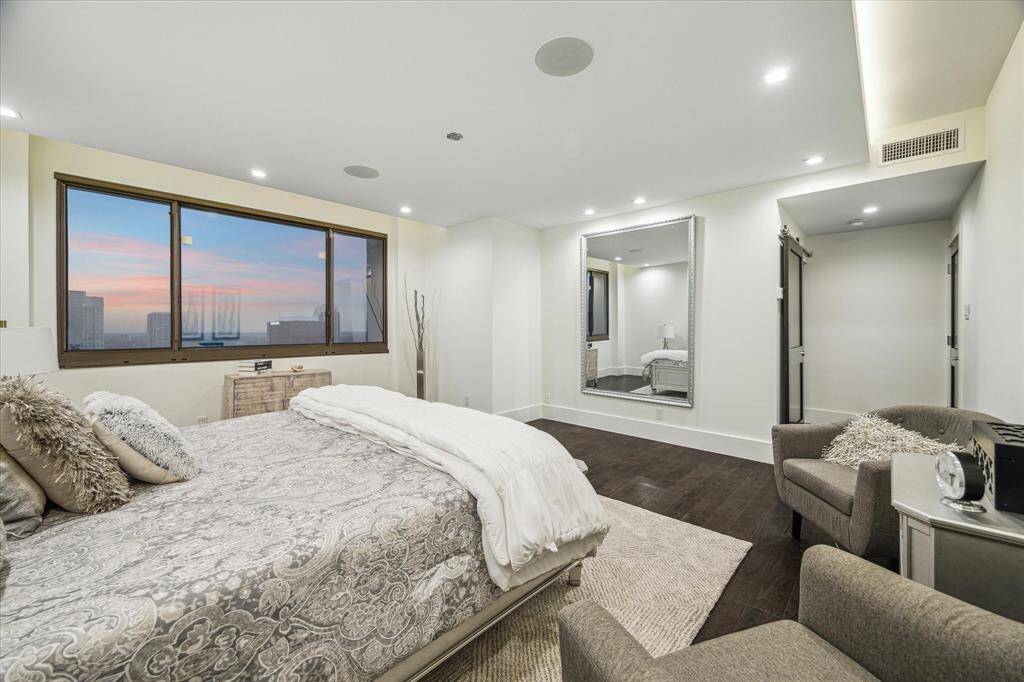 Another angle of the primary suite showcasing the sliding barn door leading to the bathroom and the hallway entry on the right.