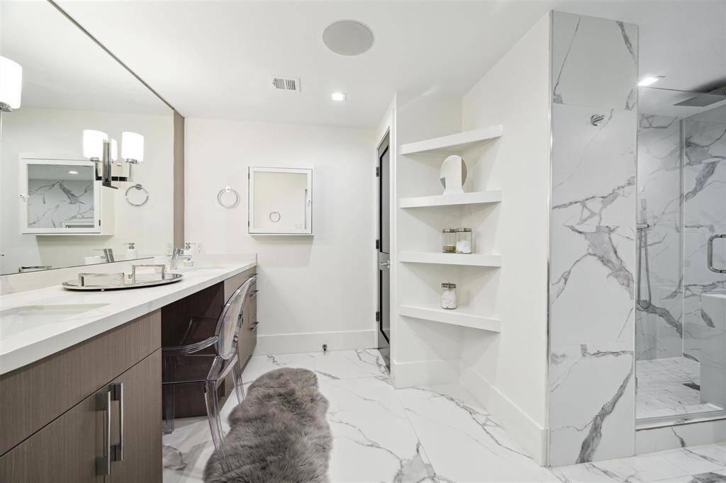 Step through the sleek slider barn door into the spa-inspired primary bathroom, featuring elegant tile flooring, recessed lighting, and built-in surround sound for a truly immersive experience.