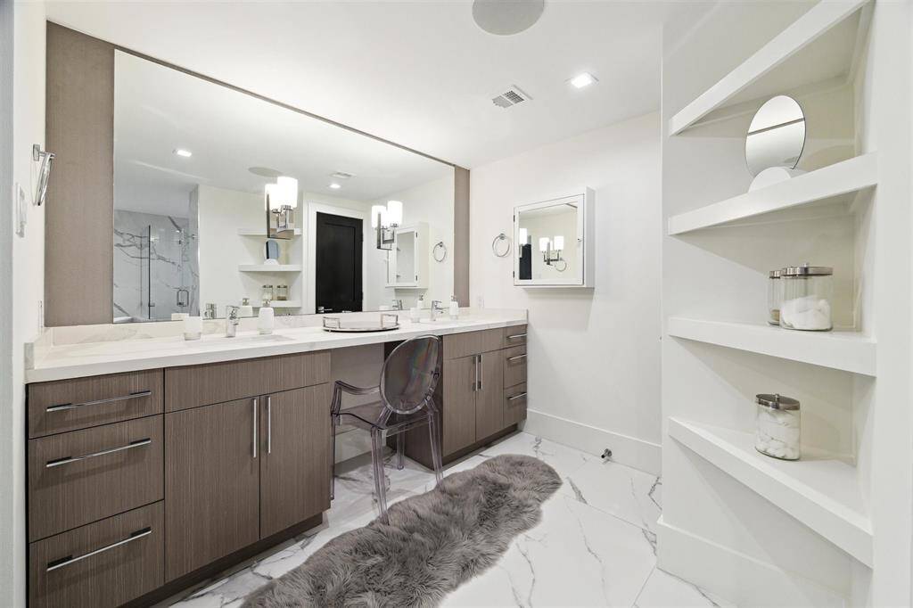 Spacious primary bathroom features a double-sink vanity, with soft-close drawers, a convenient seating area, and abundant storage.