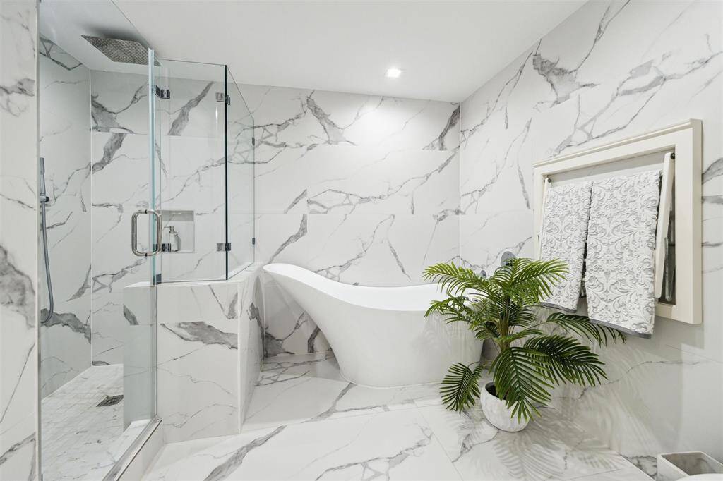Floor-to-ceiling tile creates a striking backdrop for the sleek soaking tub and walk-in shower, featuring a frameless glass enclosure for a clean, modern look.