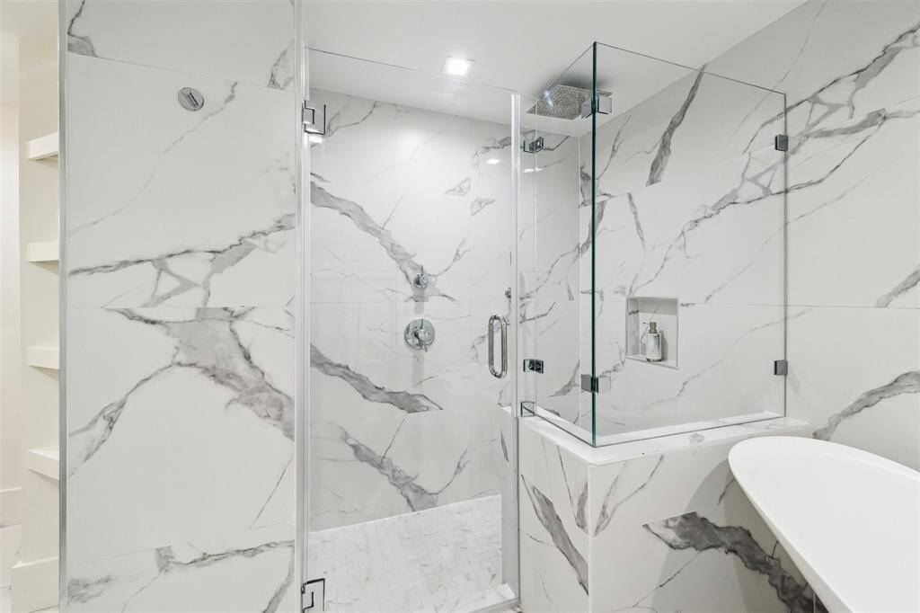 The oversized walk-in shower showcases a sleek Grohe rain shower head and hand shower, offering both style and versatility for a refreshing experience.