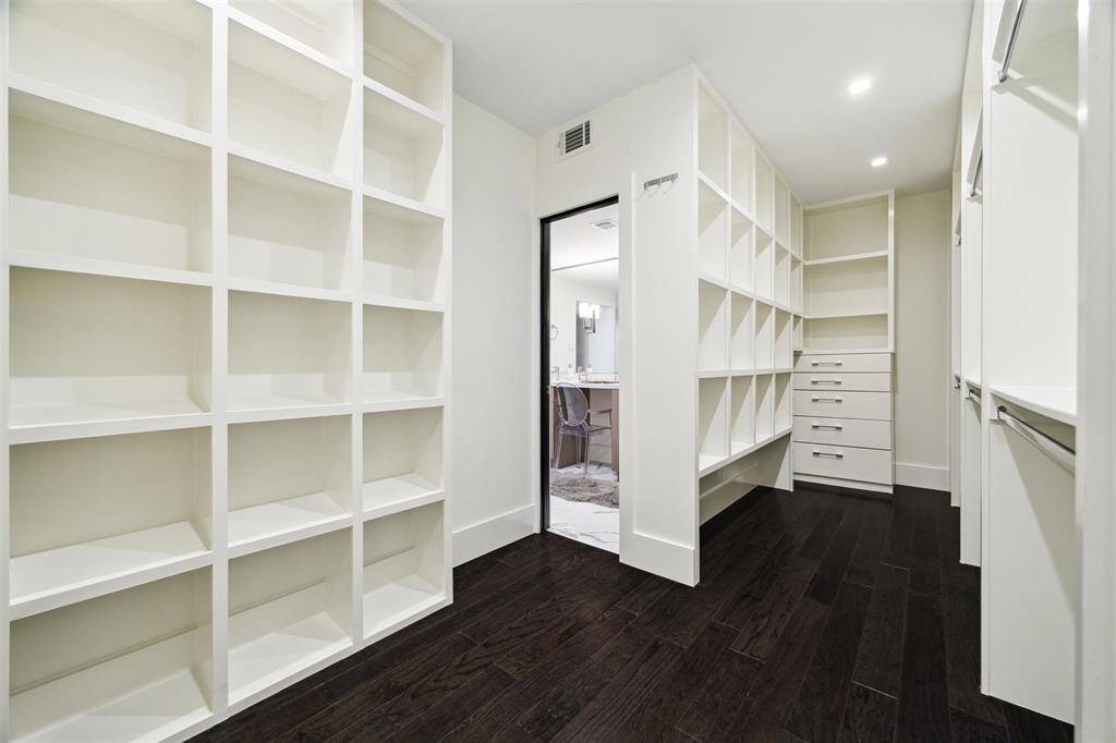 Brand-new engineered hardwood flooring extends into the spacious primary suite walk-in closet, featuring built-in shelving and soft-close drawers for ample storage.