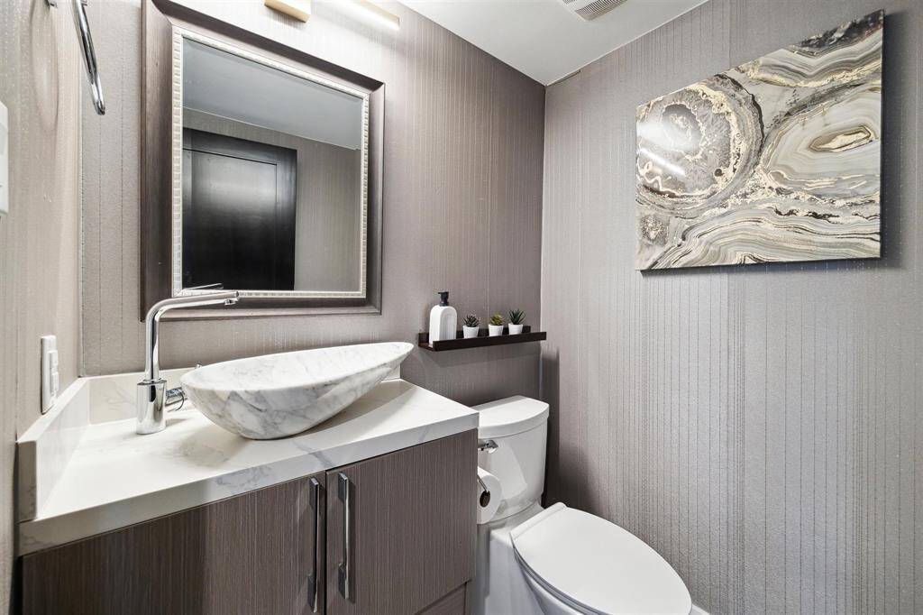 Half bath located off the foyer - fully wallpapered, featuring a sleep marble sink on a floating vanity.