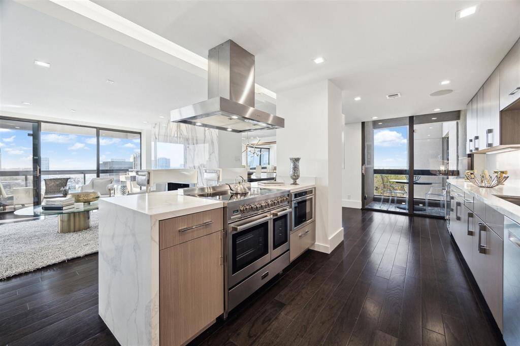 Contemporary kitchen with top-tier stainless steel appliances, Calacatta quartz countertops with a waterfall edge, and European-style cabinetry. Open to the living areas with stunning views.