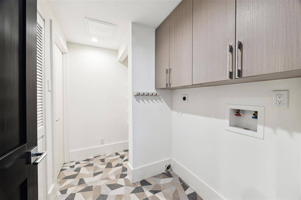 The spacious utility room off the hallway features washer and electric dryer connections, upper cabinets, and storage shelves. To the left, closets house the water heater and mechanical equipment, conveniently tucked away