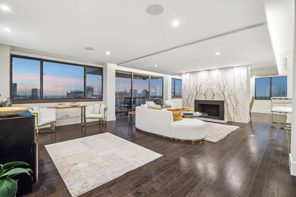 The living room is elevated by an impressive fireplace, framed by exquisite, matchbooked Calacatta gold slabs that reach from floor to ceiling, making a bold and luxurious statement.