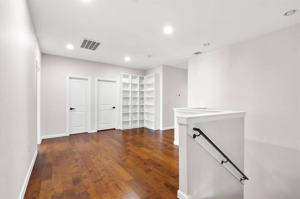 Upstairs common area with ample space, shelves and rich hard wood flooring.