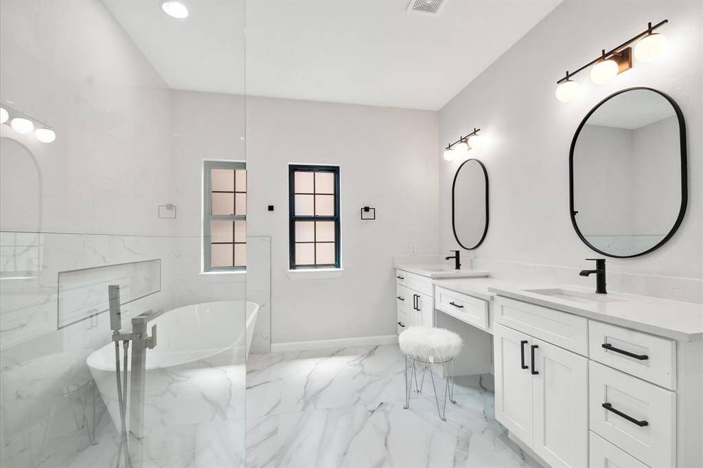 Large, well-lit, high end tile, custom cabinetry with a polished appearance.