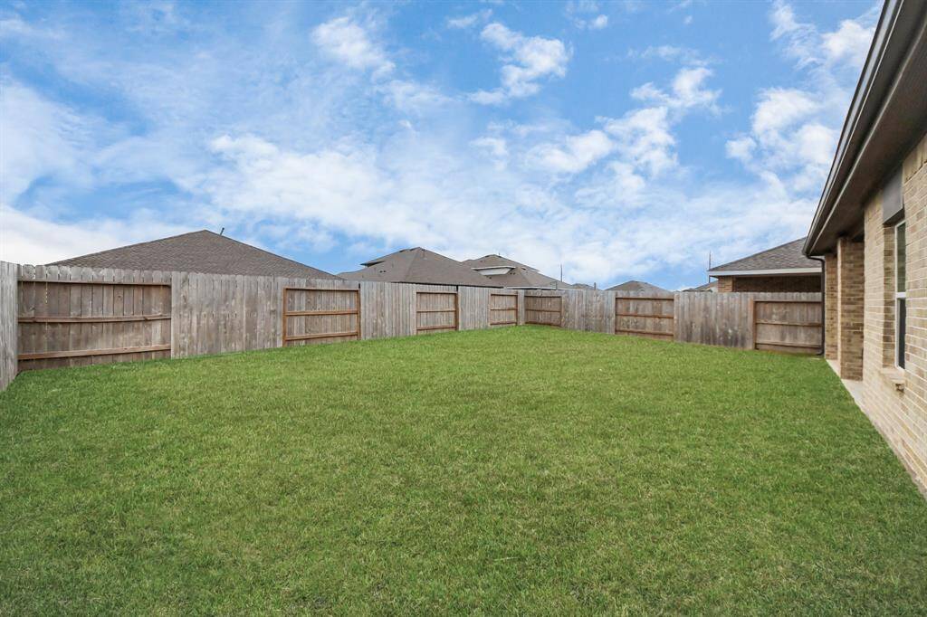 Spacious backyard with a well-maintained lawn, enclosed by a wooden privacy fence, perfect for outdoor activities and relaxation.