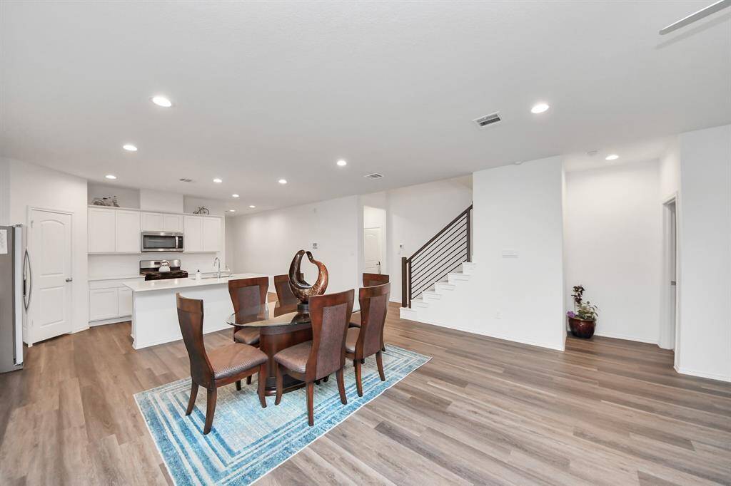 Bright and spacious family room with open access to a modern kitchen, featuring sleek floors and a stylish staircase.