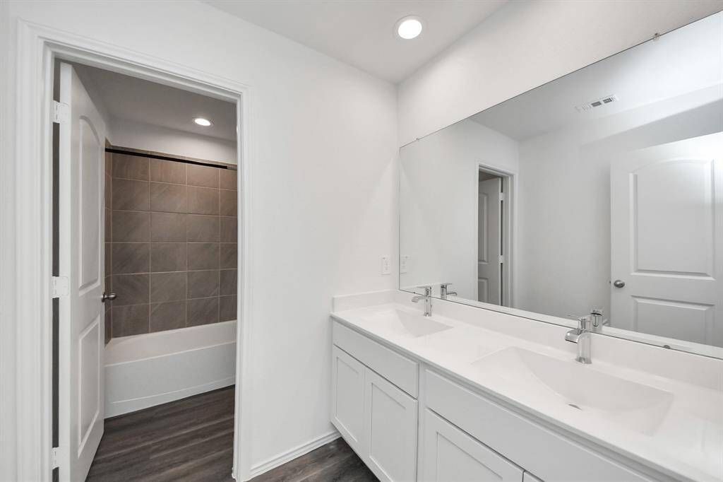 Upstairs secondary bathroom featuring dual sinks and a stylish tub.