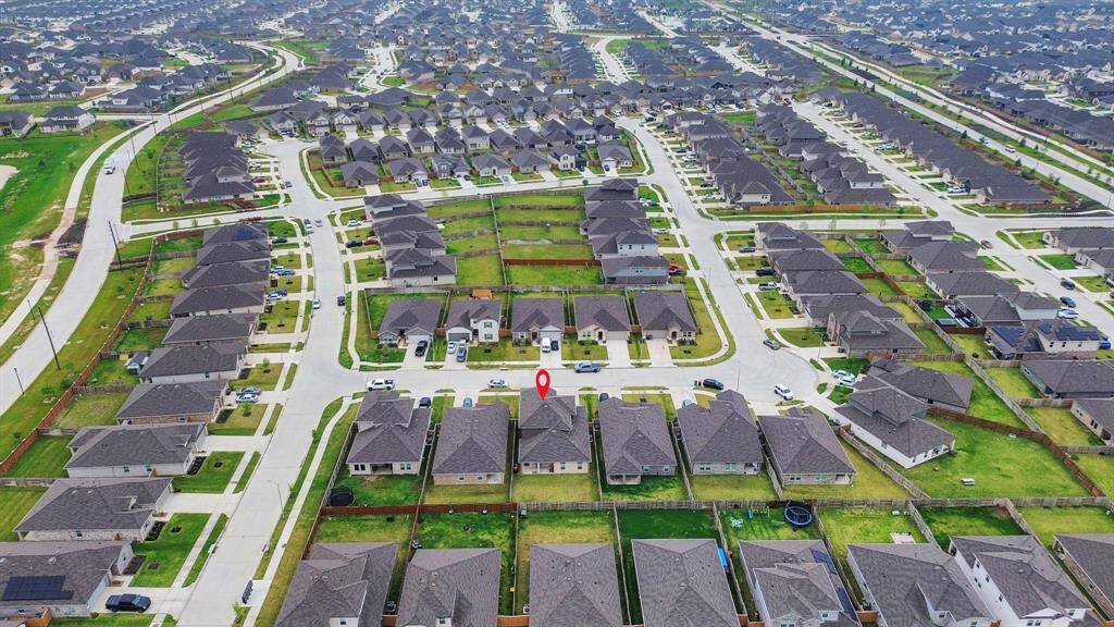 This aerial photo showcases a sprawling suburban neighborhood with neatly arranged houses, each featuring spacious yards and well-maintained streets, ideal for a family-friendly community living.