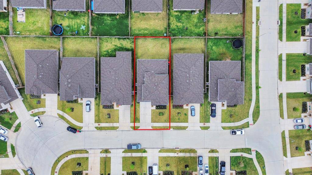 This aerial photo showcases a suburban neighborhood with a house outlined in red. The property features a fenced backyard and provides a quiet and safe environment. Nearby homes and well-maintained lawns contribute to the community's appeal.